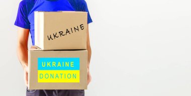 Bir adam Ukraynalı mülteciler ve kendilerini Ukrayna ve Rusya arasında savaşta bulan yoksul vatandaşlar için bir kutu yardım tutuyor. İnsani yardım kavramı. Mülteciler için bağış.