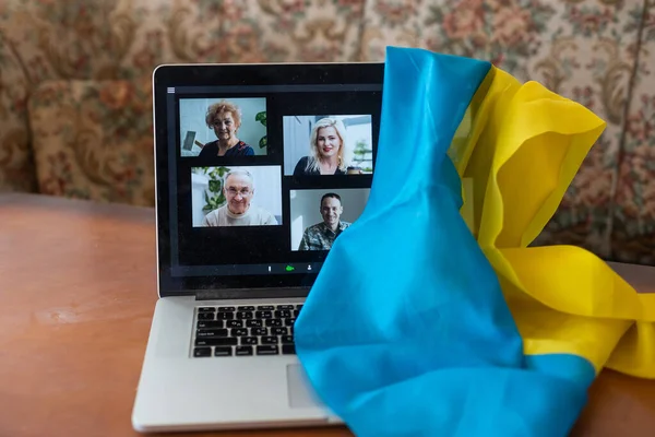 Bendera Ukraina di latar belakang dan layar digital laptop dengan konferensi video. Perang dengan Rusia. Serangan dunia maya, sanksi, keruntuhan ekonomi. Pesan untuk perdamaian dunia. — Stok Foto