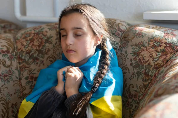 Rezem pela Ucrânia. Criança com bandeira ucraniana. Menina acenando bandeira nacional orando pela paz. — Fotografia de Stock