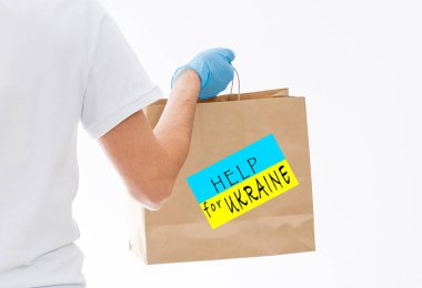 Bir adam Ukraynalı mülteciler ve kendilerini Ukrayna ve Rusya arasında savaşta bulan yoksul vatandaşlar için bir kutu yardım tutuyor. İnsani yardım kavramı. Mülteciler için bağış.