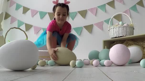 Gadis kecil yang lucu melukis telur Paskah berwarna-warni. Dia mengotori tangan dan wajahnya. Tradisi Paskah. — Stok Video