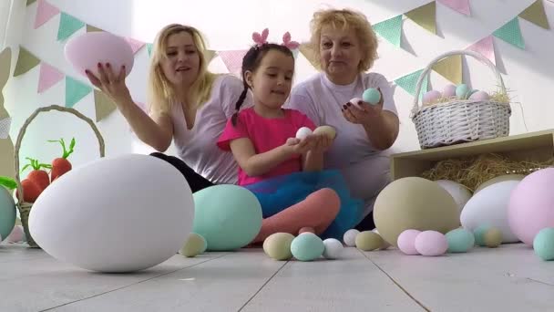 Menina compartilhando ovos decorados com mãe e avó no jantar de Páscoa com a família — Vídeo de Stock