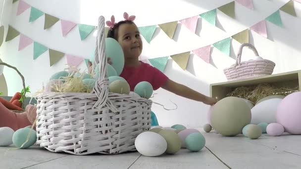 Hija comiendo Chocolate Huevos de Pascua sentado en la canasta de vacaciones conejo. — Vídeos de Stock
