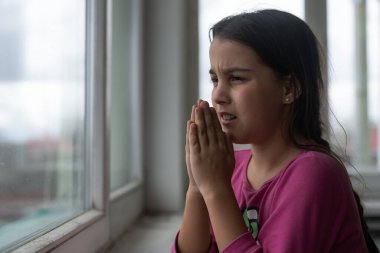 Pencereyakınında dua eden küçük kız