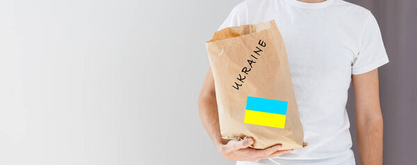 A man holds a box of aid for Ukrainian refugees and poor citizens who find themselves in a war between Ukraine and Russia. Humanitarian aid concept. Donate for refugees.