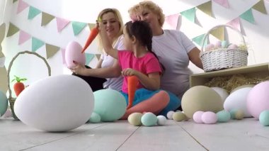 Güzel küçük kız Paskalya aile yemeğinde anne ve büyükannesine süslü yumurta ve tebrik kartı veriyor.