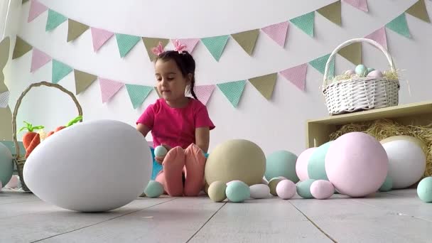 Petite fille mignonne peignant des œufs de Pâques colorés. Elle se salit les mains et le visage. Tradition de Pâques. — Video