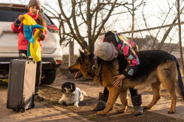 Ukrayna askeri göçü. Bavullu iki küçük kız. Ukrayna bayrağı, yardım et. Kriz, askeri çatışma