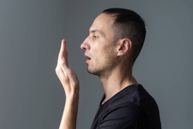 Elini ağzının önüne koyan ve nefesini kontrol eden yakışıklı bir adama yaklaş.