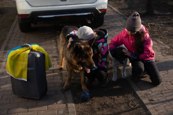 Στρατιωτική μετανάστευση της Ουκρανίας. Δύο κοριτσάκια με βαλίτσα. Σημαία της Ουκρανίας, βοήθεια. Κρίση, στρατιωτική σύγκρουση — Φωτογραφία Αρχείου