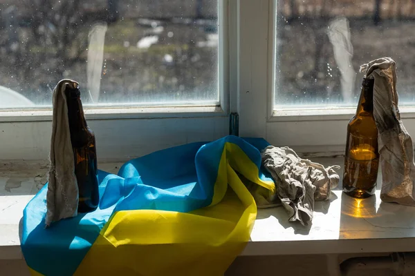 Cocktail Molotov caseiro na Ucrânia, Kiev, preparado para proteger contra invasores russos durante a ruptura entre ataques e bombardeios por mísseis russos contra a bandeira de fundo da Ucrânia — Fotografia de Stock