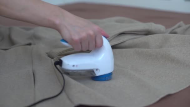 Vrouw maakt gebruik van een machine voor het verwijderen van pellet en spoelen uit kleding en stof op zwarte broek. Een modern elektronisch apparaat voor het bijwerken van oude dingen. — Stockvideo