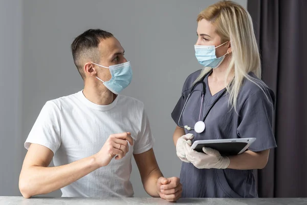 Professionelle Ärztin mit Stethoskop benutzt ein Computertablett, das neben ihrer Patientin steht — Stockfoto