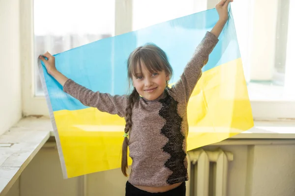Маленькая девочка, покрытая флагом Украины. Концепция положения с украинским народом в войне с Россией. — стоковое фото