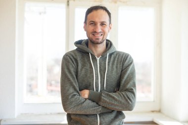 Sakallı, orta yaşlı bir adam kameraya bakıyor. Kafasında ve omuzlarında ciddi bir ifade var.