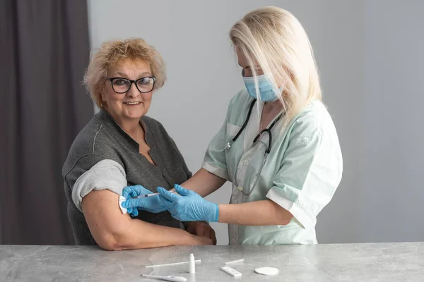 Η ηλικιωμένη γυναίκα δείχνει ευτυχισμένη μετά το εμβόλιο. Ηλικιωμένη γυναίκα που δείχνει το χέρι της με επίδεσμο μετά από εμβολιασμό. — Φωτογραφία Αρχείου