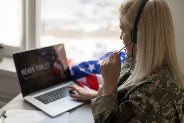 Vrij vrouwelijke soldaat werken met laptop zittend aan tafel in het hoofdkwartier van gebouw. — Stockfoto