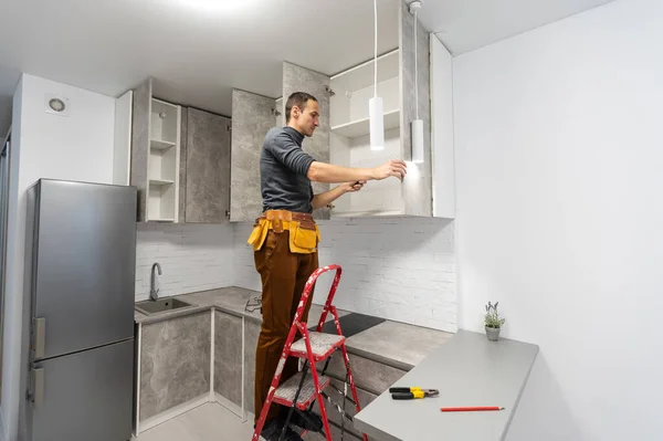 Elektriker, ein männlicher Elektriker steht auf der Treppe mit Verkabelung in der Hand und Strippen, Reparatur Licht zu Hause, Reparaturarbeiten, Anrufmeister, Elektriker Mann Reparatur Licht — Stockfoto