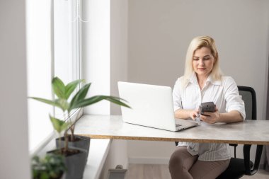 Mutlu, neşeli, güzel iş kadını imajı. Ofiste dizüstü bilgisayar kullanarak oturuyor.