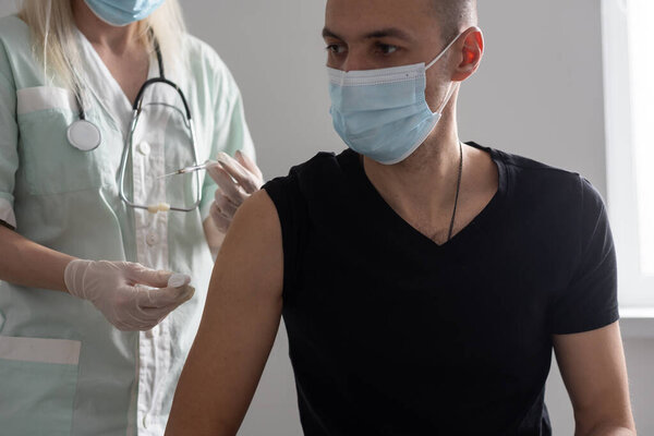 Doctor makes vaccination in the shoulder of patient in a hospital