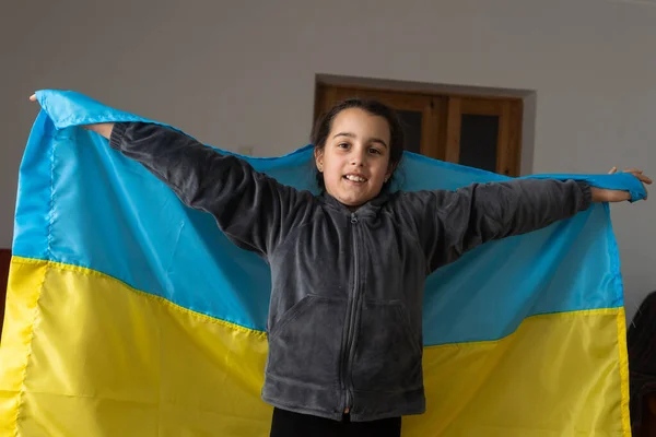 Menina coberta com bandeira da Ucrânia. Conceito de estar com a nação ucraniana em guerra com a Rússia. — Fotografia de Stock
