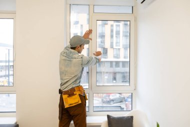 Efendinin plastik bir pencerede çift camlı pencereyi değiştirmesi, yan görünüm