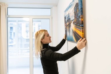 Resim bezi baskısı. Galeri ambalajıyla fotoğraf çeken bir kadın. Fotoğraf parlak sentetik tuvale basılmış ve sedye çubuğuna gerilmiş.