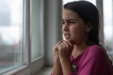 Küçük kız sabah beyaz masada dua ediyor. El dua eden küçük kız, inanç, maneviyat ve din için dua konseptine sarılmış eller..