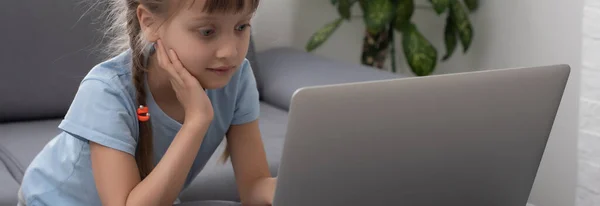 Menina entediada com laptop em casa. Criança gira a fazer trabalhos de casa no computador. Educação online moderna, conceito de comunicação e tecnologia, espaço de cópia. — Fotografia de Stock