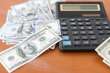 Hesap makinesi ve dolar ahşap masada..