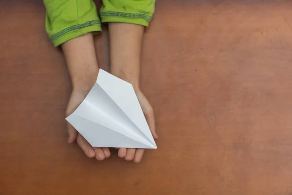 Χάρτινο αεροπλάνο σε παιδικά χέρια. — Φωτογραφία Αρχείου