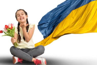 Eğitim, okul, sanat ve mutluluk konsepti - Ukrayna bayrağı taşıyan küçük kız öğrenci okulda sarı ve mavi renkli.
