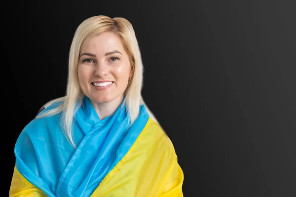 Schöne junge Frau mit der Fahne der Ukraine auf dunklem Hintergrund. — Stockfoto