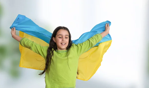 Ребенок несет развевающийся синий и желтый флаг Украины, изолированный на белом. День независимости Украины. День флага. День Конституции. Девушка в традиционной вышивке с флагом Украины — стоковое фото