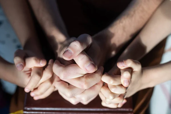 Top view of parents and kid holding empty hands together at wooden table, space for text. Family day — Stock Photo, Image