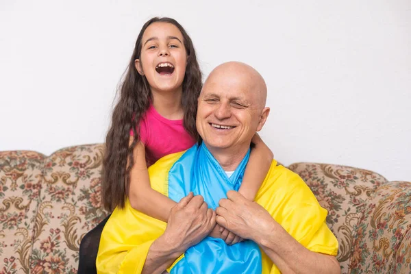 Ukrainian Grandfather and granddaughter with laptop and flag of Ukraine — Stock Photo, Image