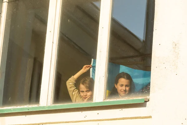 Маленькая девочка в окне своего дома с раскрашенным желто-голубым флагом Украины, мир в Украине, остановить войну, протест и патриота, родина Украины. — стоковое фото