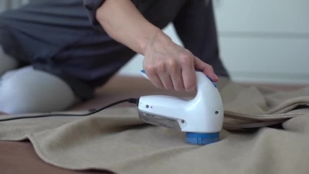 Беспроводное устройство для очистки трикотажных тканей от линьки. Женщина снимает шпагат со свитера. — стоковое видео