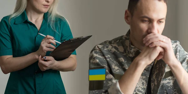 Um médico militar examinando um soldado ucraniano em uma camuflagem militar, psicólogo — Fotografia de Stock