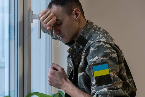 Воїн українського чоловіка, одягнений у військовий піксель, утворює жовто-синій прапор України. — стокове фото