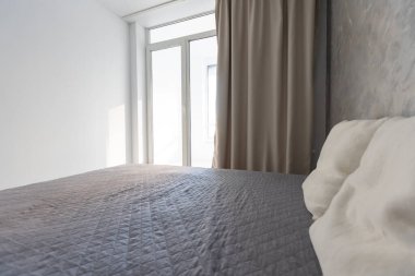 Minimalist tarzda bir yatak odası. Battaniye ve yastıklı iki kişilik yatak