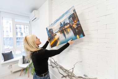 Resim bezi baskısı. Galeri ambalajıyla fotoğraf çeken bir kadın. Fotoğraf parlak sentetik tuvale basılmış ve sedye çubuğuna gerilmiş.