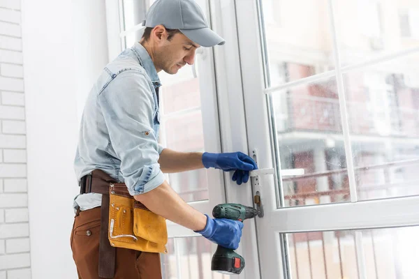 Byggnadsarbetare installerar fönster i huset. Handyman fastställande fönstret med skruvmejsel — Stockfoto