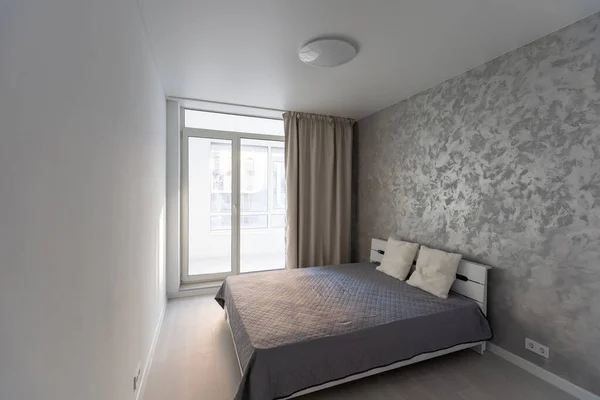 Stílusos belső modern hálószoba kényelmes bútorokkal. Két ágyas ágy takaróval és párnákkal, tükör és cserepes növény szürke falon háttér a modern otthon függönyökkel, napkitörés — Stock Fotó