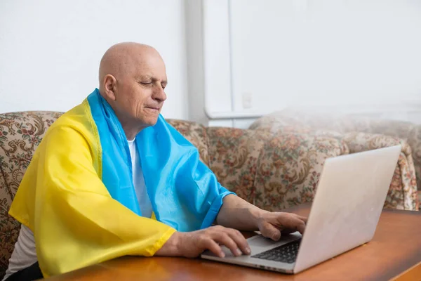 Man sits on a work with a laptop computer and flag Ukraine — Stock Photo, Image