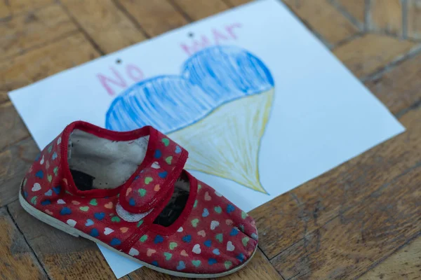 Niños zapatos y la bandera de Ucrania, la guerrala guerra en Ucrania. — Foto de Stock