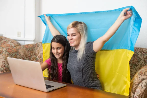 Online digitális média támogatás Ukrajna számára. Szabadság és hazafiság koncepció. anya és lánya laptop és ukrán zászló — Stock Fotó