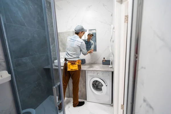 El trabajador instala el espejo en el baño — Foto de Stock