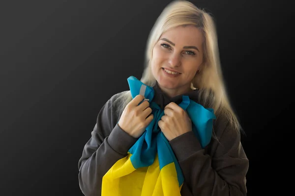 Schöne junge Frau mit der Fahne der Ukraine auf dunklem Hintergrund. — Stockfoto