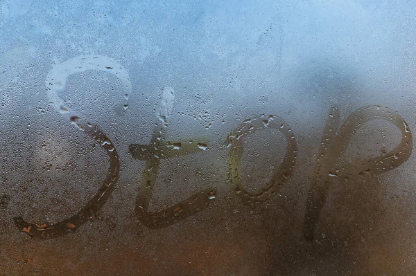 La palabra parada escrita en la noche ventana húmeda de vidrio de primer plano con fondo borroso — Foto de Stock
